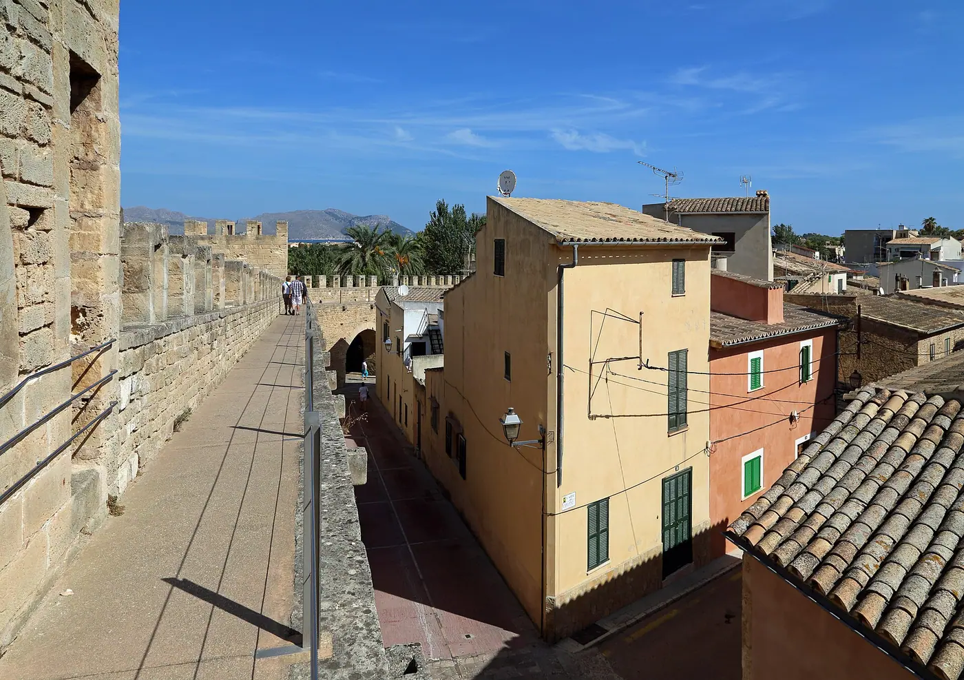 Promenade sur le chemin de ronde des murailles d'Alcúdia, au-dessus des toits.