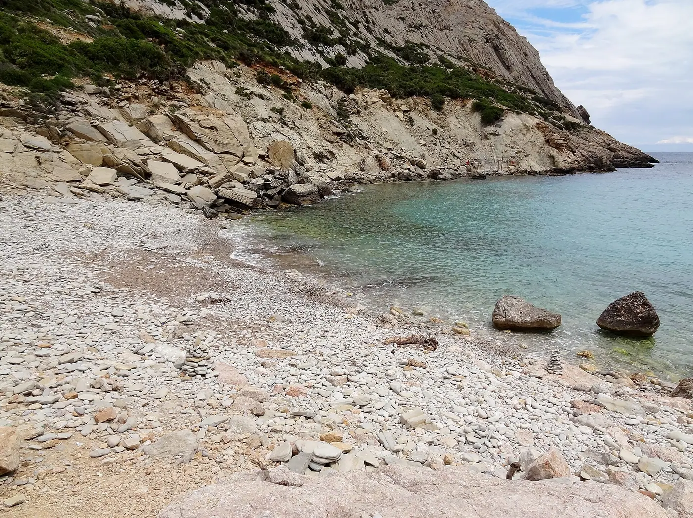 Eau turquoise léchant les galets clairs de Cala Bóquer.