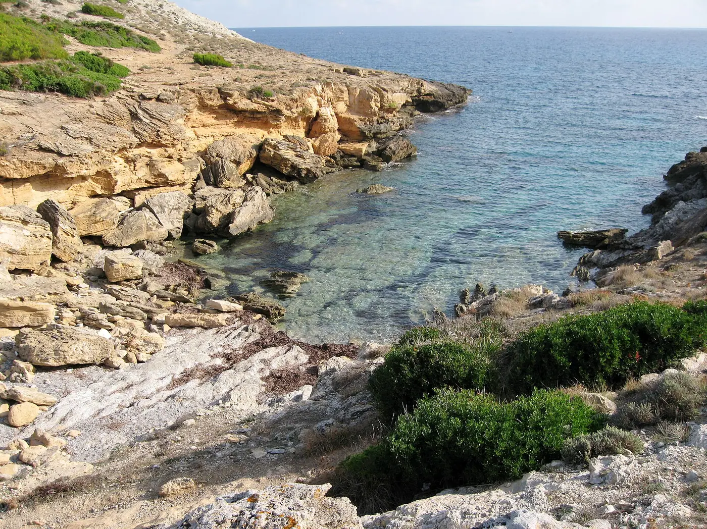 Crique étroite de Cala Estreta encadrée de rochers clairs.