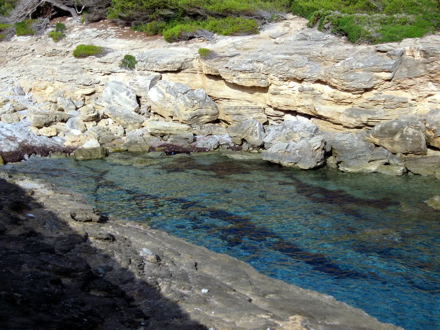 Eau bleu vif entre les rochers blancs de Cala Estreta.