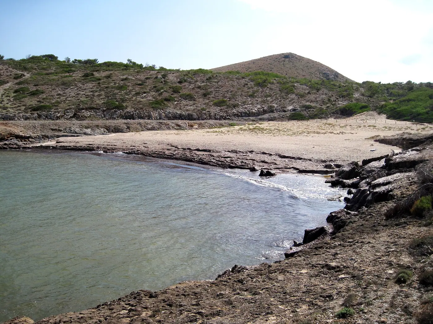 Crique de Cala Mitjana bordée de rochers, eau claire.