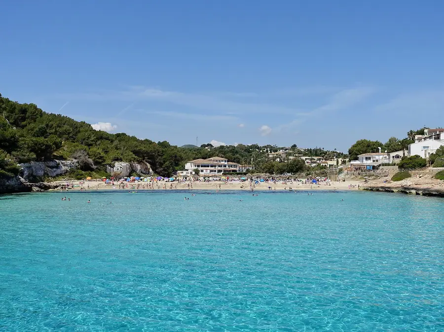 Eaux turquoise et plage de S'Estany d'en Mas (Cala Romàntica), bordée de pins.
