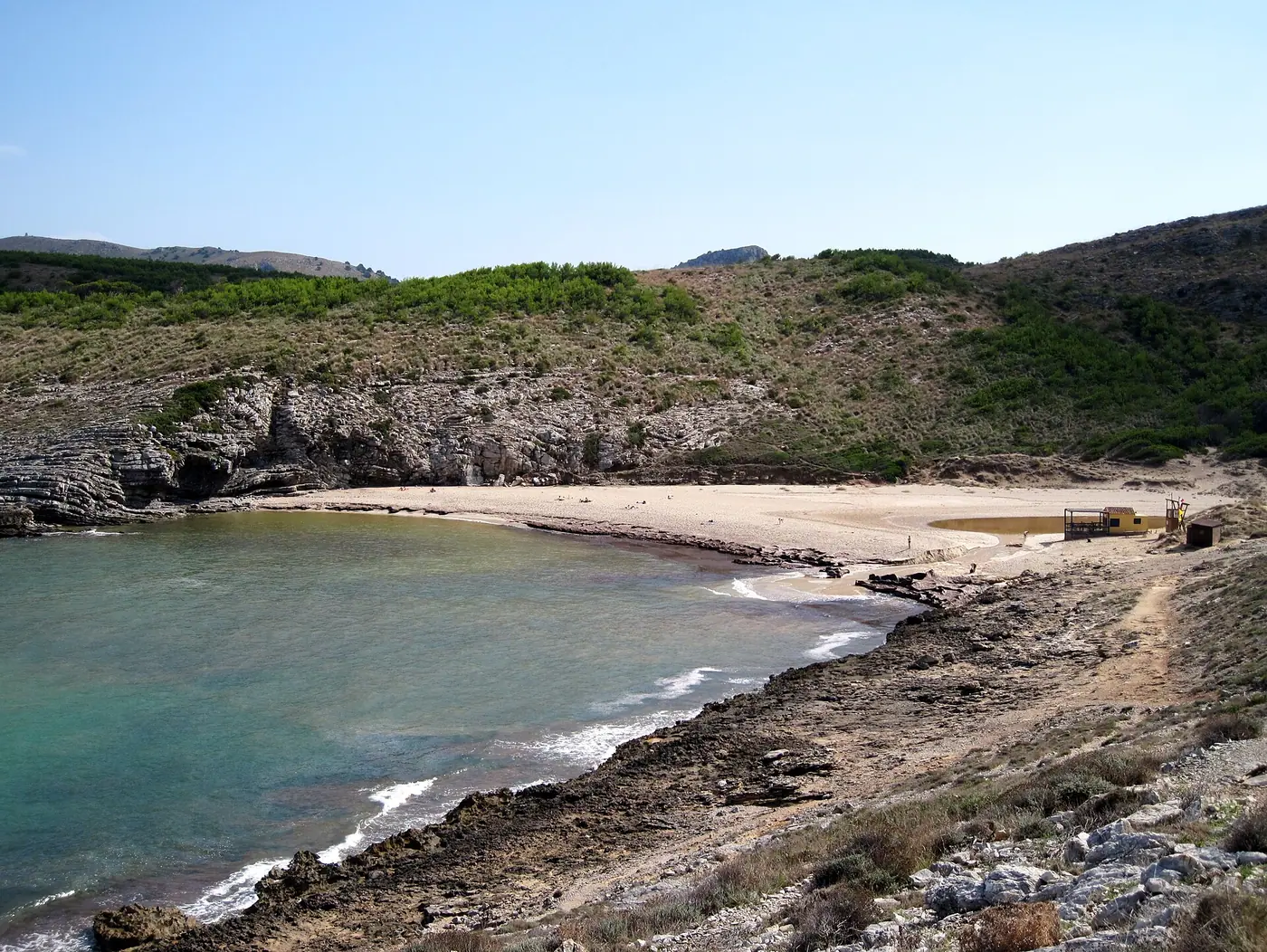 Vue élevée sur Cala Torta, mer turquoise et maquis méditerranéen.