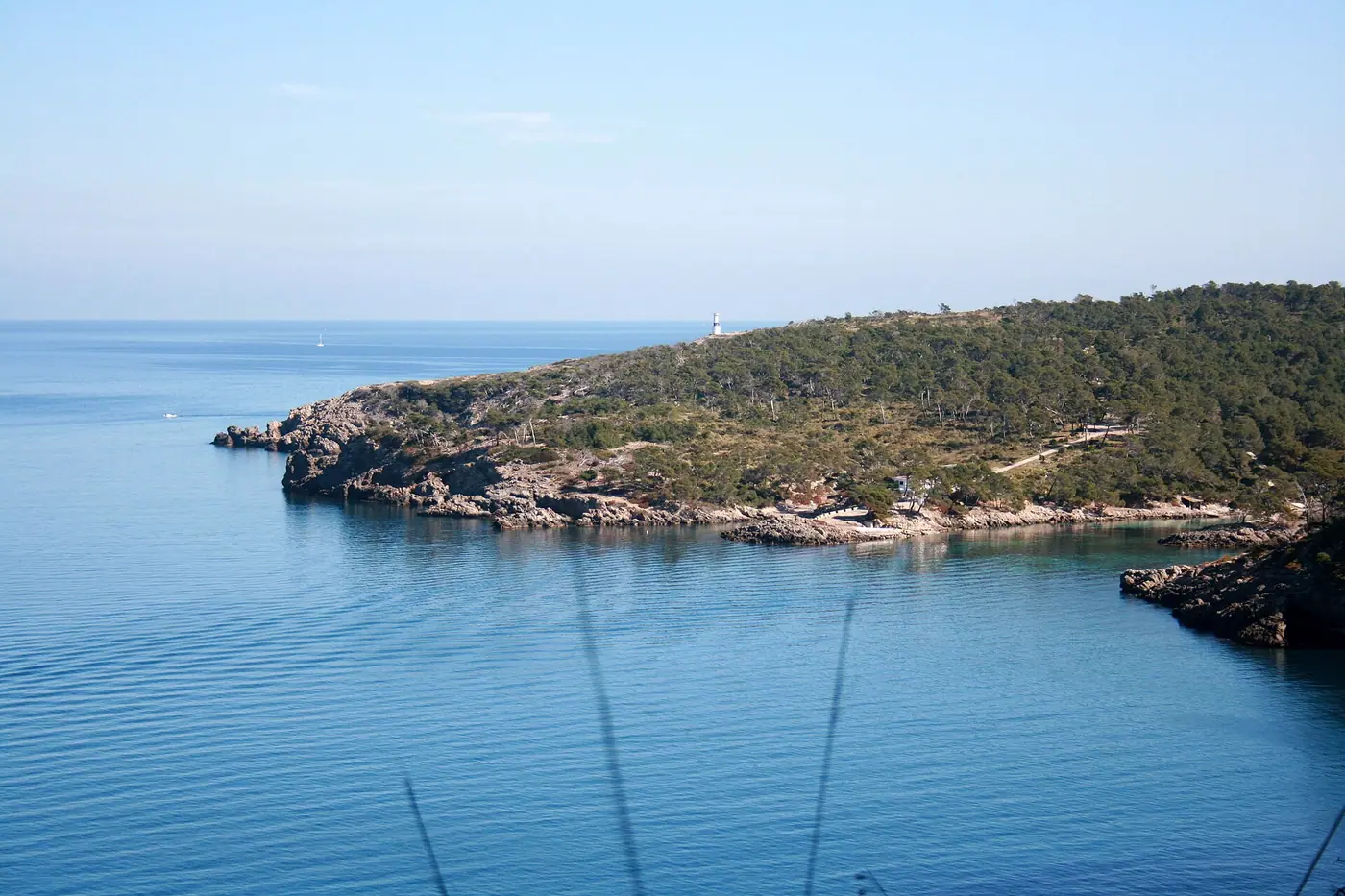 La baie calme du Cap des Pinar bordée de pins méditerranéens.