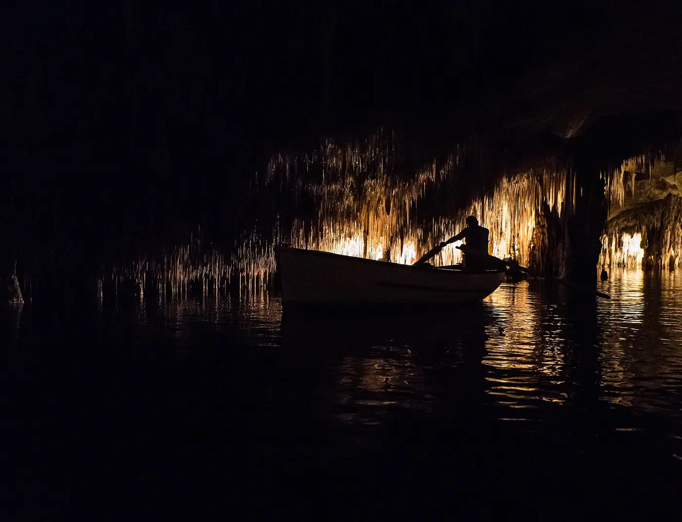 Une barque glisse sur le lac Martel, illuminé par des jeux de lumière féeriques.