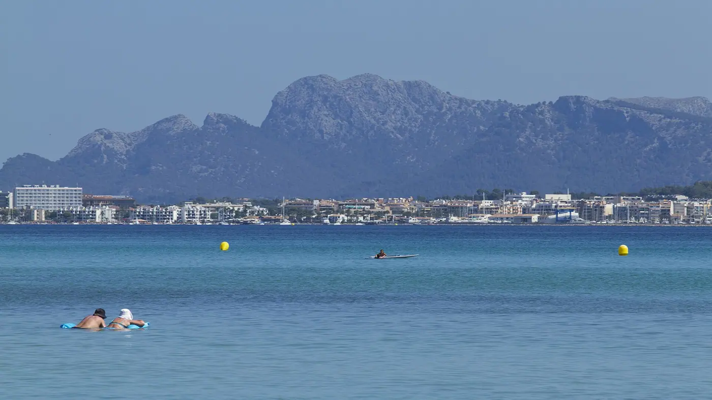 Bande turquoise vive de la baie d'Alcúdia côté Platja de Muro, montagnes en toile de fond.